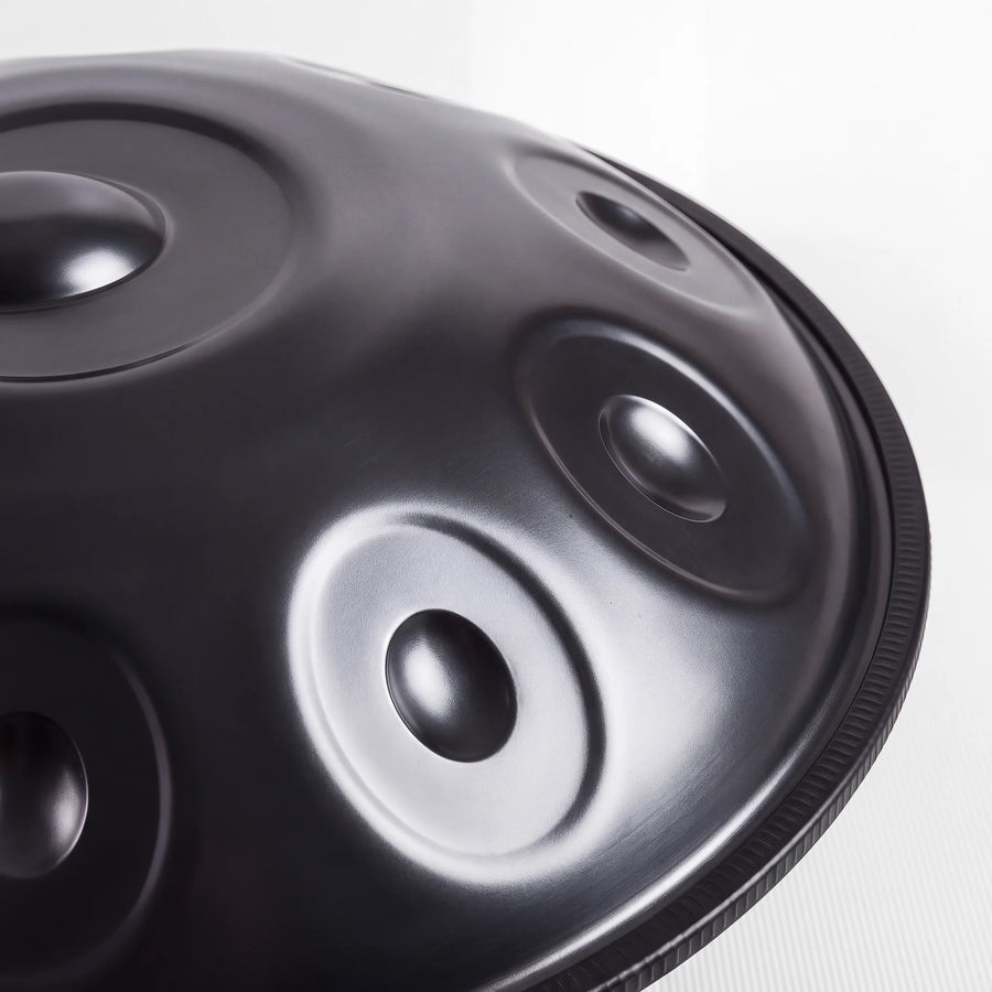 Close view of a Sonant D Kurd handpan with 10 notes in a black finish, showing its tone fields and rim — 9
