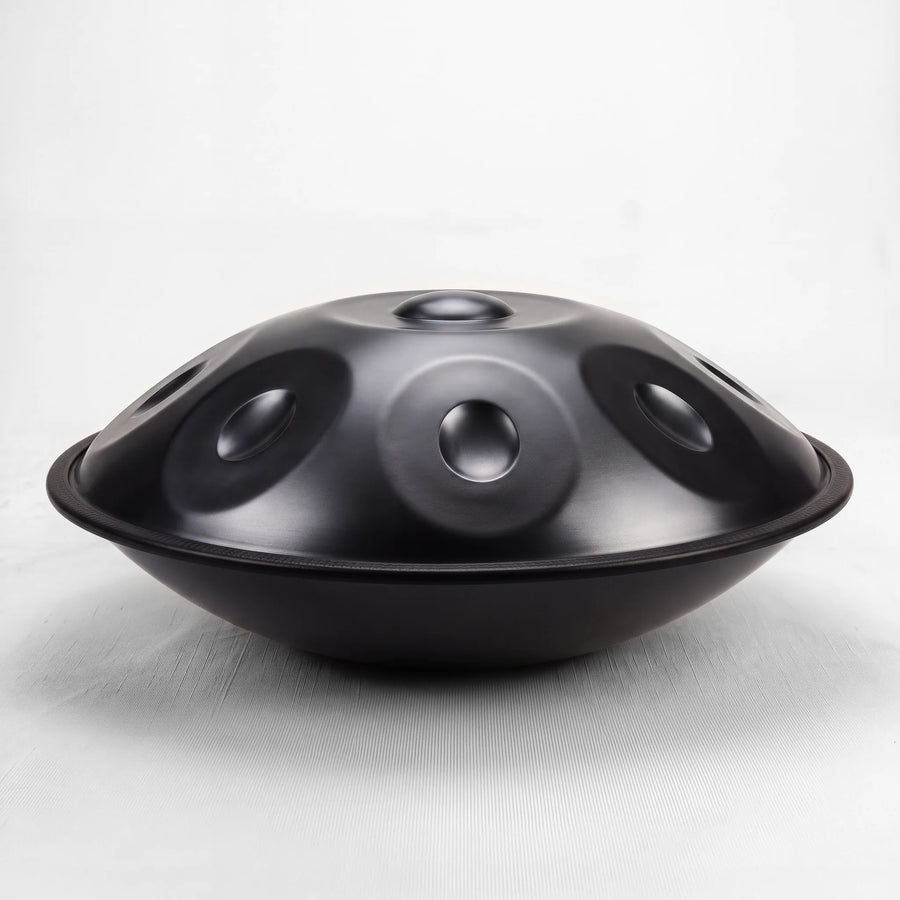 Sonant D Kurd handpan with 12 notes in a black finish, viewed from the side with its rim and rounded bottom shell — 14