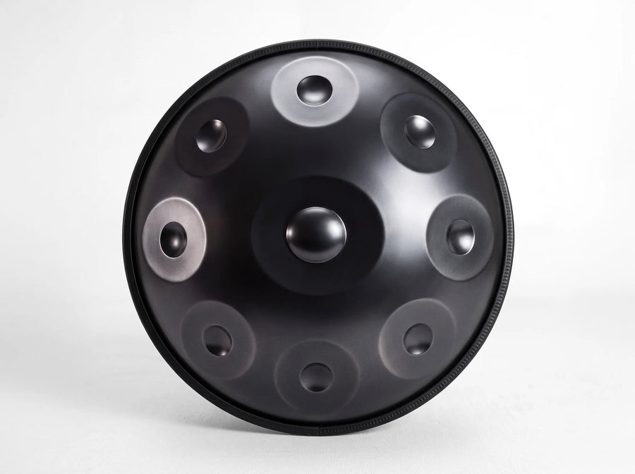 Front view of a black stainless steel handpan with 9 notes, showing its central dome and 8 surrounding notes