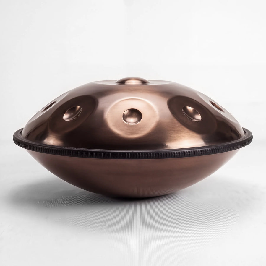 Sonant D Kurd handpan with 9 notes in a bronze finish, viewed from the side with its rim and rounded bottom shell — 14